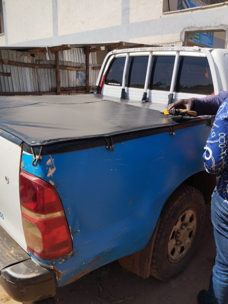 Installing a black flat bed cover on a Toyota Hilux pickup at Bungoma Seatcovers Ventures workshop