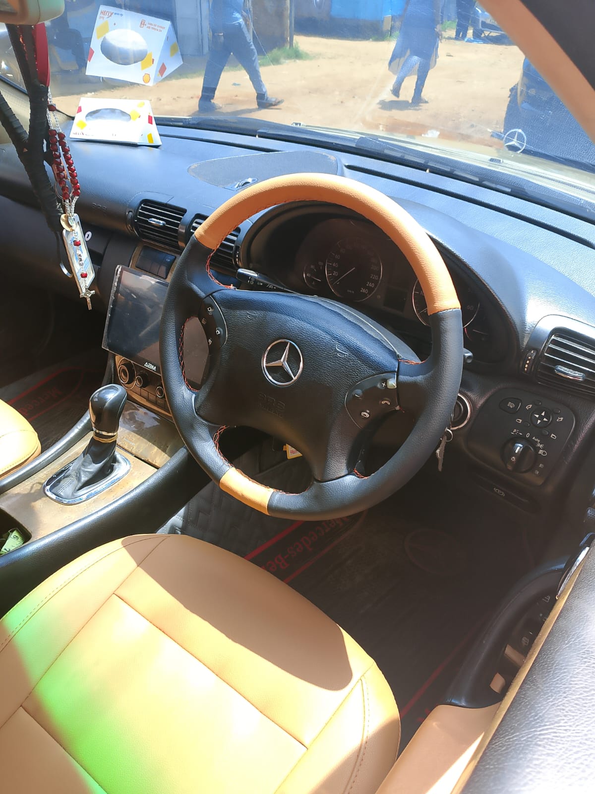 Tan and black leather steering wheel cover fitted on a Mercedes wheel