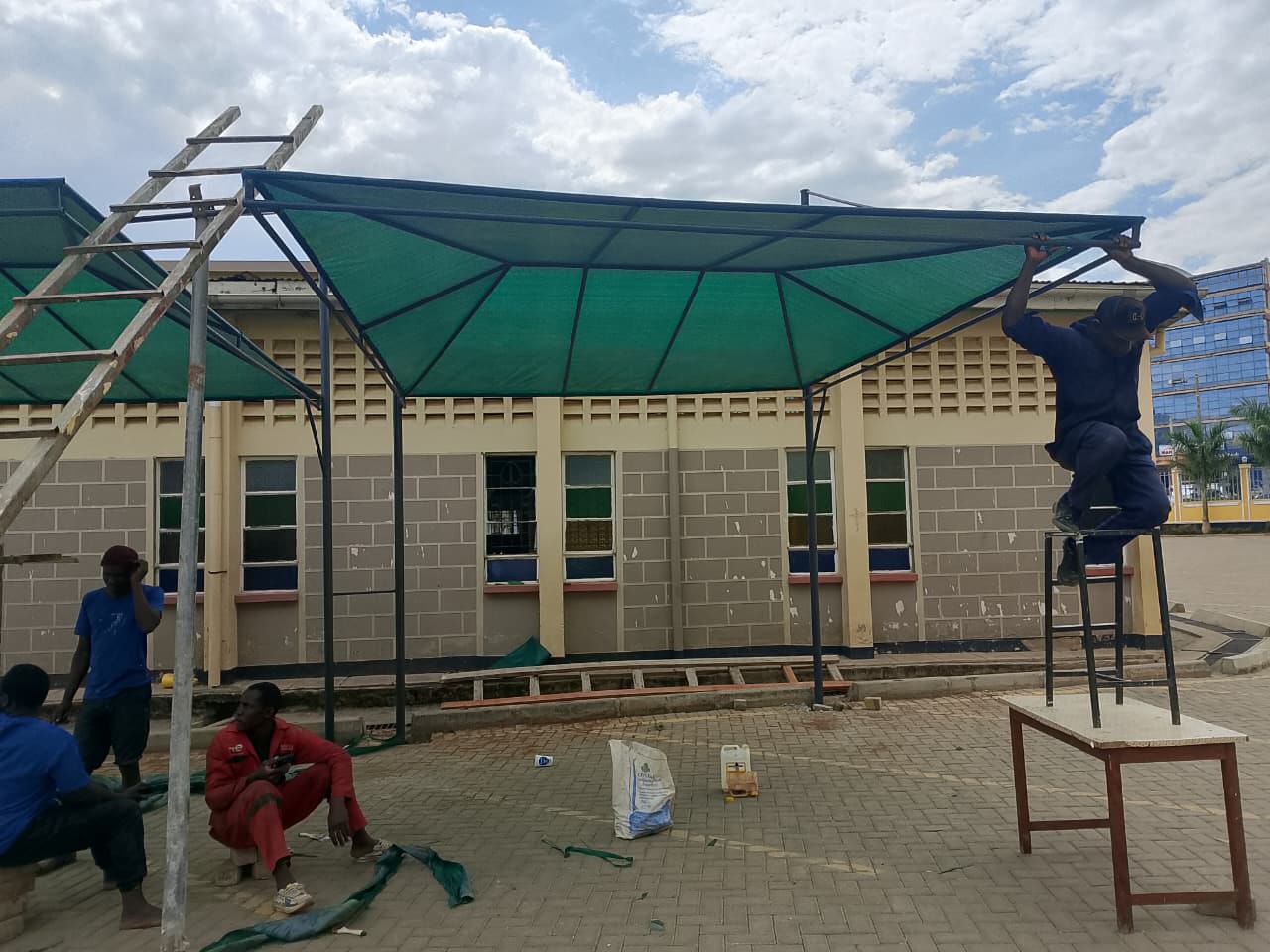 Crew installing a green shade net over a parking space